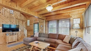 A log cabin interior with a large wooden ceiling, a television, a sectional sofa, and a fireplace. - Lakefront Home With Private Dock, Canoe & Kayak, Fast Wifi, and Firepit - dog OK (Greenville)