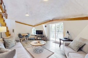 A spacious living area with a sofa, coffee table, TV, and dining table. - Geodesic Dome w/ Riverfront Deck, Lovely Views, & High-speed Wifi - Dogs Welcome (Boothbay)