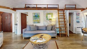 Una sala de estar acogedora con un sofá, una mesa de centro y una escalera que lleva a un altillo.