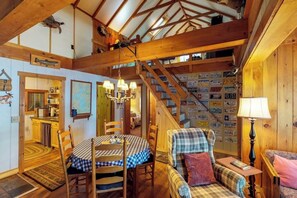 A rustic interior with a dining table, chairs, a sofa, a lamp, and a staircase. - Dog-friendly Lakefront Cabin With Full Kitchen, Firepit, Free Wifi, Great Views (Greenville)