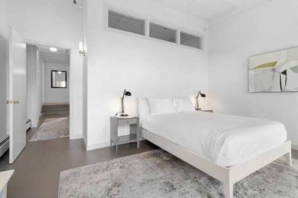 Un dormitorio moderno con cama, mesitas de noche, una alfombra y un cuadro en la pared.