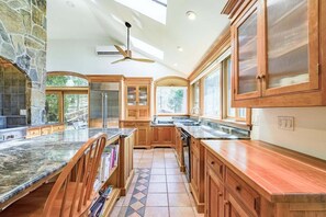 A spacious kitchen with granite countertops, wooden cabinets, and a stone fireplace. - Riverside on Hopkins, Waterfront With Dock, 4 Bed, (Camden)