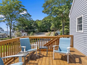 A deck with outdoor seating, overlooking a residential area with houses and trees. - Boothbay Harbor Home With Water Views Near Dining & Whale Watching (East Boothbay)