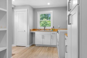 A kitchen with white cabinets, a window, and a sink. - Newly-built Waterfront Home With Fast Wifi, Furnished Deck, & Washer/dryer (Waldoboro)