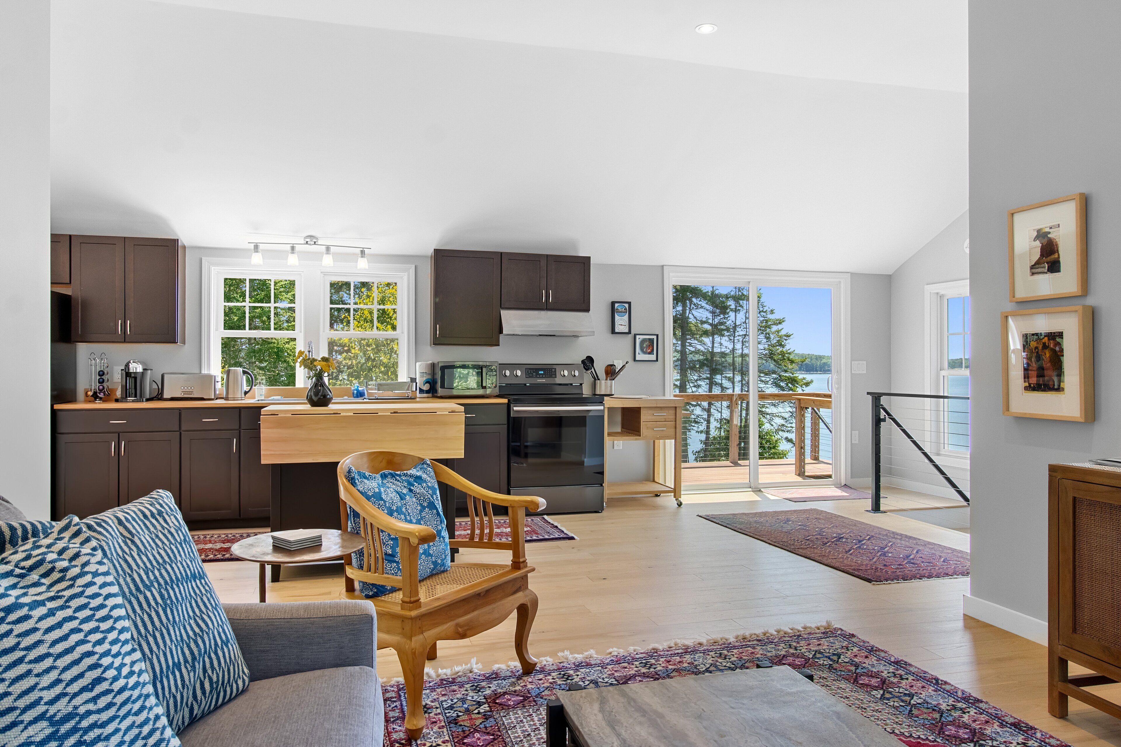 A spacious living area with a sofa, a wooden chair, a dining table, and a kitchen with a view.