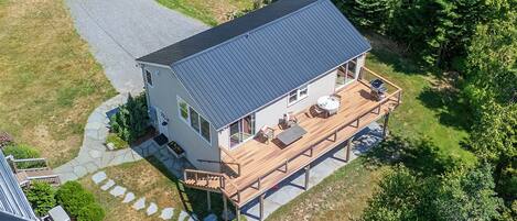 A two-story house with a deck, a stone pathway, and a lawn.