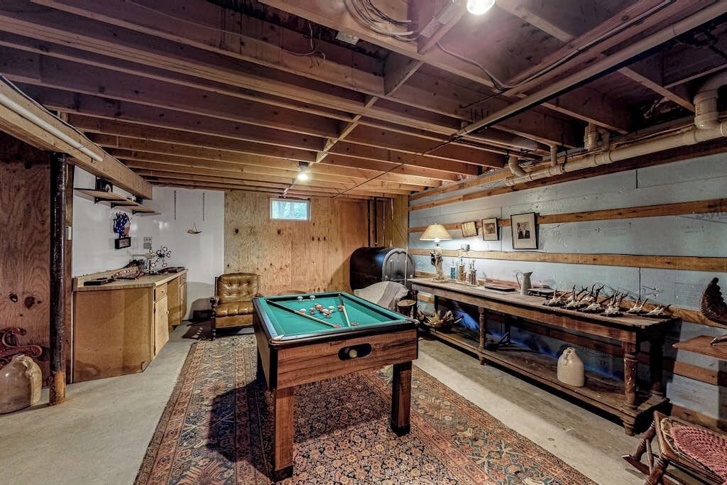 Una habitación con mesa de billar, paredes de madera, un escritorio y una silla.