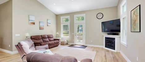 A living room with a brown leather sofa, a flat-screen TV, and a fireplace.