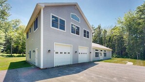 A two-story house with a garage, a covered porch, and a driveway. - Newly Renovated Home w/ Large Yard & Great Kitchen - Near Downtown & Acadia (Bar Harbor)