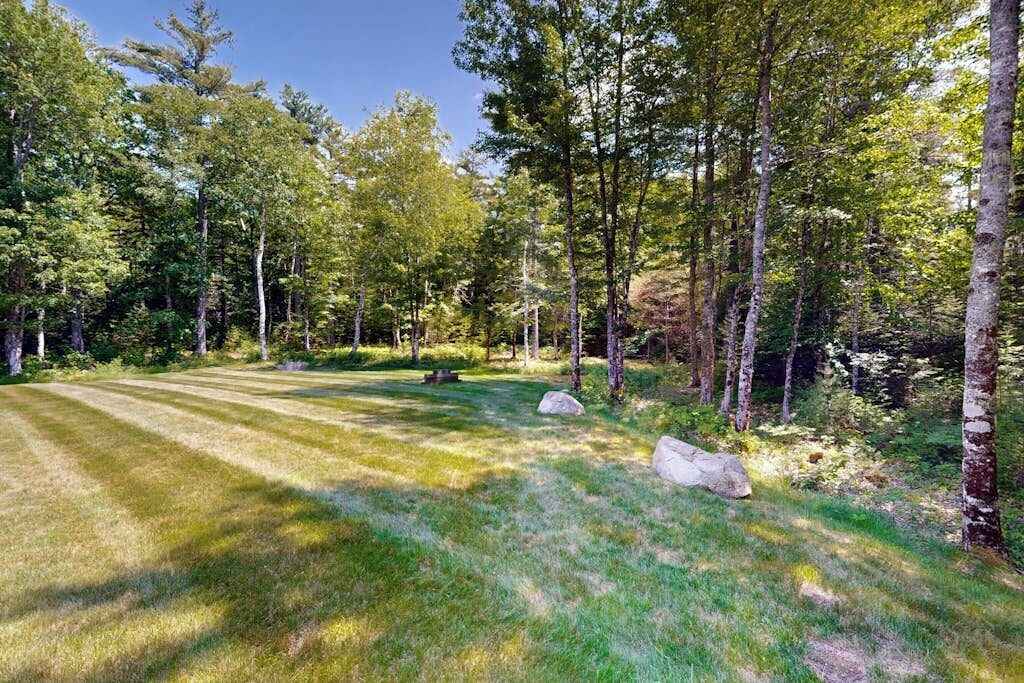 Une zone boisée avec une pelouse bien entretenue, de gros rochers et des arbres.