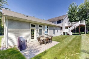 Ein Haus mit Terrasse, Grillüberdachung und einer Treppe zu einer oberen Ebene.