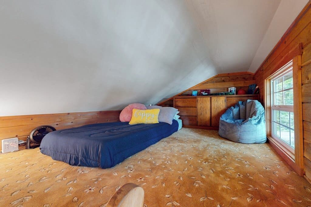 Une chambre mansardée chaleureuse, avec un lit, un fauteuil poire et une petite kitchenette.