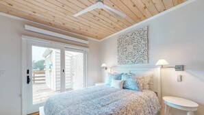 A bedroom with a large bed, a ceiling fan, a decorative wall piece, and a small table. - Bayfront Cottage on Mill Cove w/ Private Dock & Furnished Deck - Walk Downtown (Boothbay Harbor)