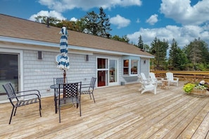A wooden deck with outdoor furniture, a covered seating area, and a building with a white exterior. - Bayfront Cottage on Mill Cove w/ Private Dock & Furnished Deck - Walk Downtown (Boothbay Harbor)