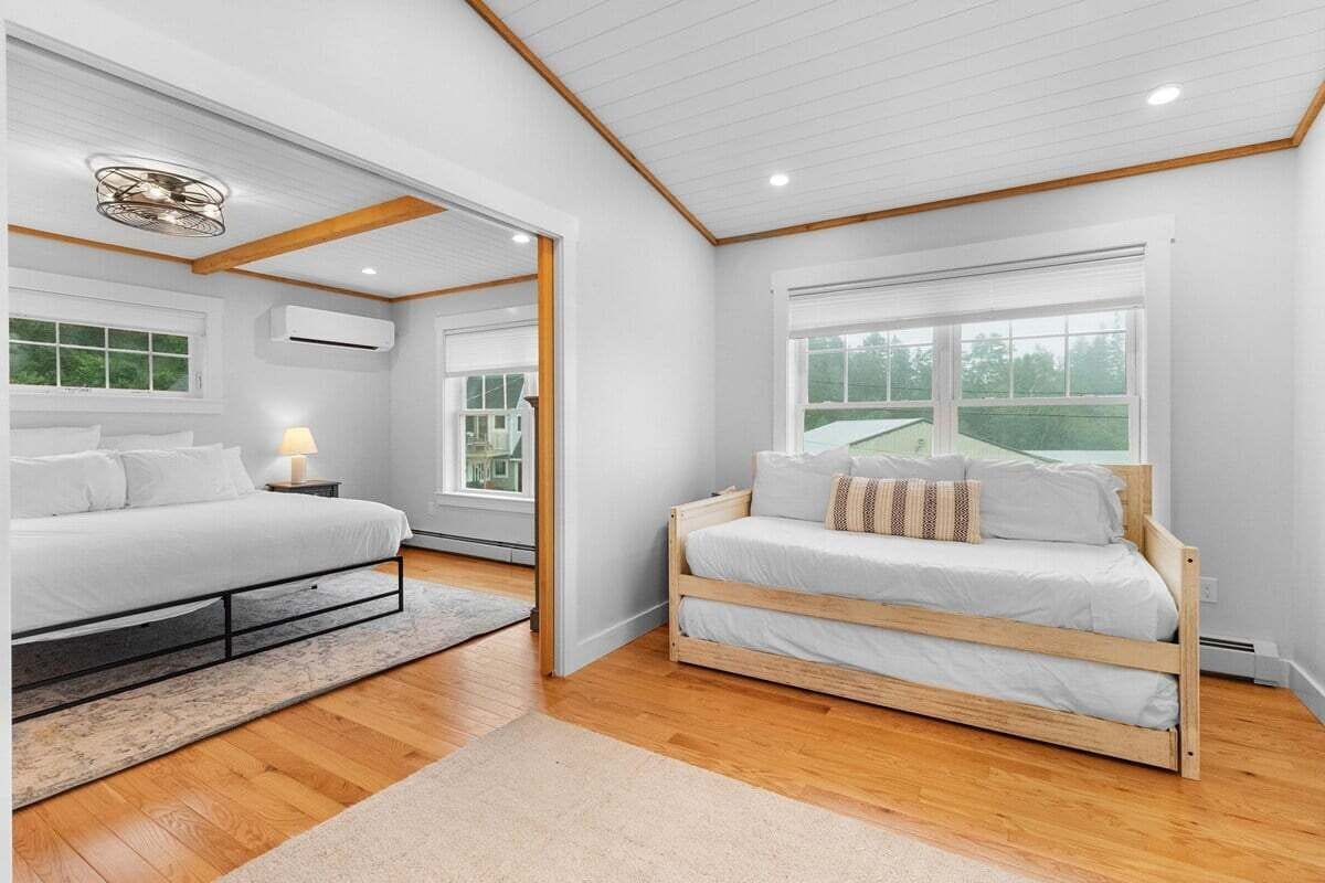Ein Schlafzimmer mit einem Bett, einem Nachttisch, einer Lampe, einem Fenster und einer Deckenleuchte.