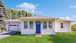 Una casa de un piso con puerta azul, un garaje y un pequeño porche.