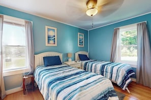 A bedroom with two beds, a ceiling fan, and two windows with curtains. - Charming Cottage With Cozy Comfort and Easy Access to Outdoor Adventures (Ellsworth)
