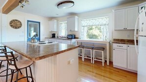 Una cocina con armarios blancos, encimera de granito, hervidor y microondas.