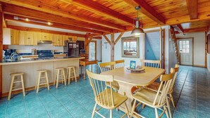 Une cuisine spacieuse dotée de meubles en bois, d’un îlot central avec des tabourets et d’un coin repas avec une table et des chaises.