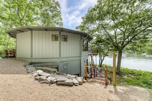 A small, light-colored wooden structure with a porch and a stone pathway leading to it. - Unique Oceanfront Home With a Deck, Tons of Natural Light, & Amazing Views (Wiscasset)