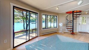 Ein geräumiges Zimmer mit großen Fenstern, einer Wendeltreppe und Blick auf ein Gewässer.