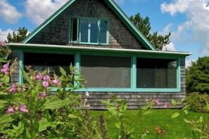 A house with a gabled roof, a porch with green trim, and a garage. - Peaceful Coastal Cabin With Screened Porch, Water View of the Cove, Dog-friendly (Owls Head)