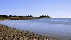 Une rivière paisible, avec des berges rocheuses et des arbres en arrière-plan.