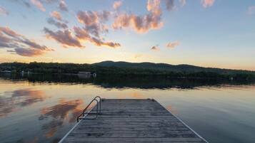 A wooden dock extending into calm water with a sunset sky.