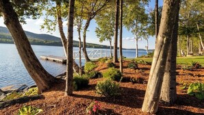 Uma propriedade à beira-lago com cais, árvores e um jardim bem cuidado.