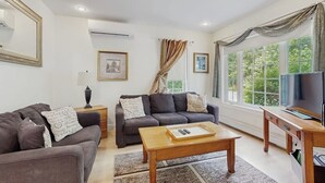 A living room with a sofa, a coffee table, a TV, and a window with curtains. - Ideally Located Home w/ Deck, Wifi & Washer/dryer - Walk Into Town & Acadia (Bar Harbor)