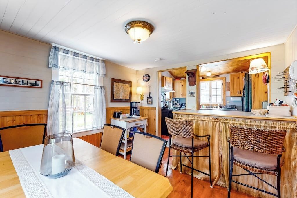 A cozy dining area with a wooden table, chairs, and a kitchen in the background.