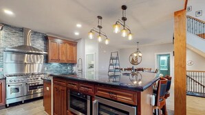 A modern kitchen with stainless steel appliances, wooden cabinets, and a central island. - Luxurious Waterfront Home With Deck, Firepit, hot Tub, Fireplace, & Pool Table (Boothbay)