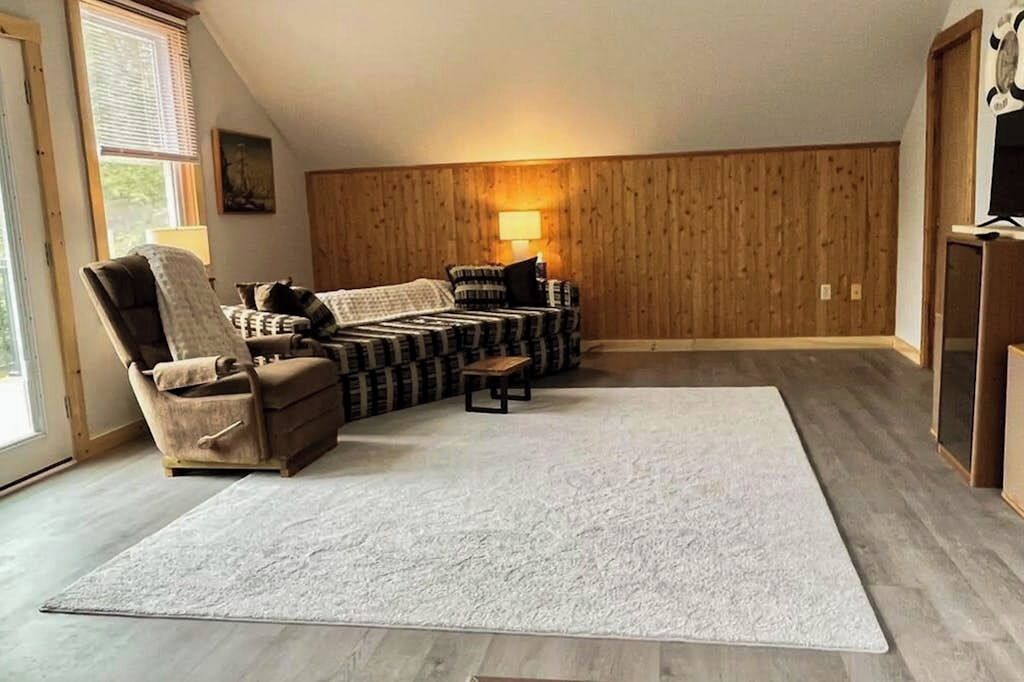 Een kamer met een modulaire bank, een verstelbare fauteuil, een klein tafeltje en een groot vloerkleed.