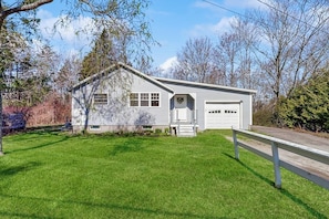 A single-story house with a garage, a front porch, and a well-maintained lawn. - Coastal Bungalow With Large Yard, Beautiful Kitchen, & Great Location (Boothbay Harbor)
