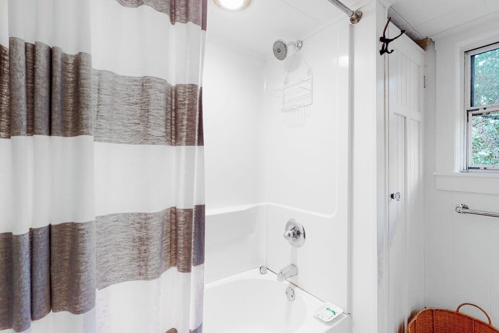 Een badkamer met een bad, een douche en een raam.