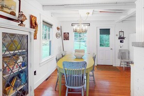 A dining area with a round table, chairs, a chandelier, and a door leading outside. - Waterfront Dog-friendly Cottage With Amazing Views, Deck, Grill, & Washer/dryer (Cushing)