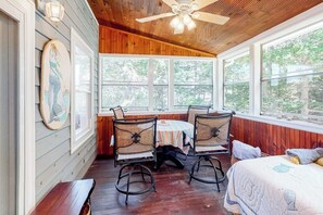 A room with a wooden ceiling, a ceiling fan, a table with chairs, a bed, and large windows. - Secluded Waterfront Home With Firepit, gas Grill, Kayaks, Dock, Balcony, & Patio (Phippsburg)