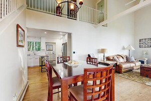 A spacious living area with a dining table, chairs, a sofa, and a staircase leading to an upper level.