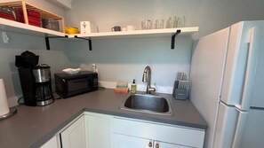 A kitchen with a microwave, coffee maker, sink, and a refrigerator.