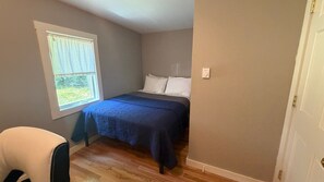 A bedroom with a bed, a window, and a door. - 36 Main (Castine)