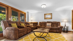 A living room with a sectional sofa, a coffee table, and two floor lamps. - Lakefront Chalet-style Home With Large Deck, a Dock & Beautiful Lake Views (Greenville)