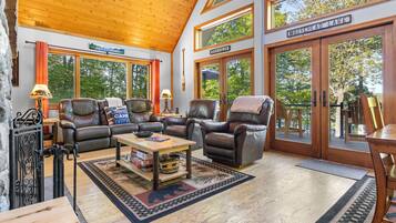 A cozy interior with leather sofas, a wooden coffee table, and large windows offering views of the outdoors.