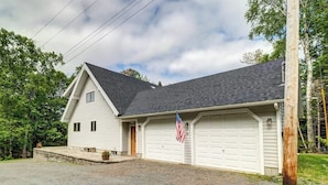 A two-story house with a garage, a front porch, and an American flag. - Lakefront Chalet-style Home With Large Deck, a Dock & Beautiful Lake Views (Greenville)