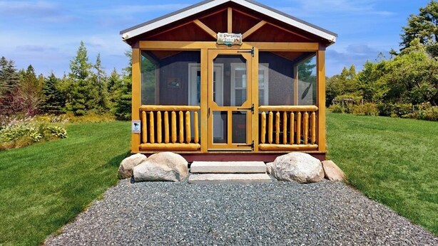 A small wooden cabin with a porch, a sign above the door, and a gravel path leading to it. - Acadia Lights (Sullivan)