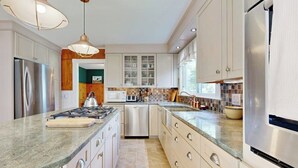 A modern kitchen with stainless steel appliances, a granite countertop, and white cabinetry. - Acadia Lights (Sullivan)