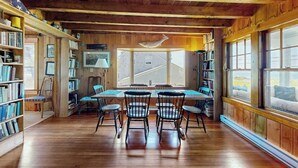 Um interior de madeira com uma mesa de jantar e cadeiras, estantes e janelas amplas.