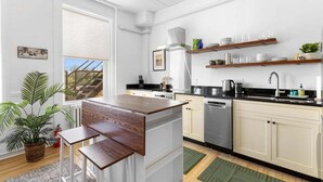 A modern kitchen with white cabinetry, a wooden island, and a view of a balcony. - Kimball Apartment, Modern Studio on Main Street Ro (Rockland)
