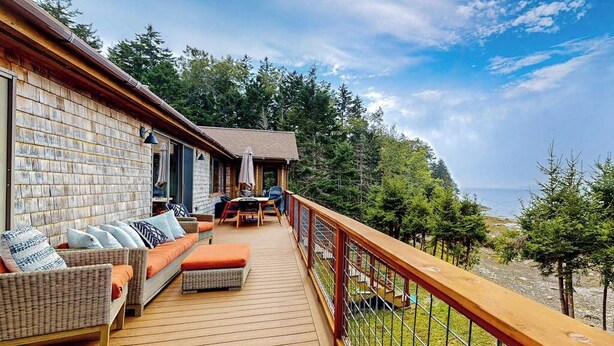 A wooden deck with outdoor furniture, a railing, and a view of the ocean. - Renovated Oceanfront Home With Stunning View & Pebbly Beach - Snowbird-friendly (Tenants Harbor)