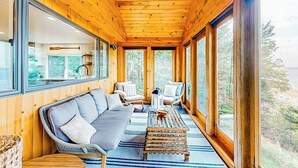 A wooden interior with a sofa, chairs, and a dining area. - Renovated Oceanfront Home With Stunning View & Pebbly Beach - Snowbird-friendly (Tenants Harbor)