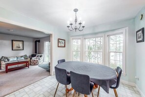 A dining area with a table, chairs, and a chandelier. - Idyllic Waterfront Home With Furnished Deck, Grill, Sweeping Views & Private W/D (Waldoboro)